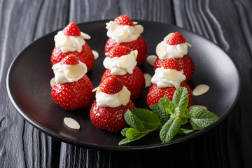 Wall Mural - beautiful strawberry dessert with almonds and whipped cream on a plate close-up on a table. horizontal