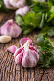 Fototapeta Miasto - Garlic. Fresh garlic bulbs on old wooden board. Red violet garlic.