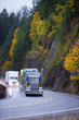 Long haul Semi trucks convoy in rain autumn windnig road