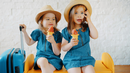 Two little girls eat ice cream at home while waiting for a summer vacation