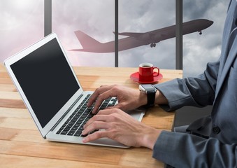 Poster - Businessman using laptop in airport with plane at window