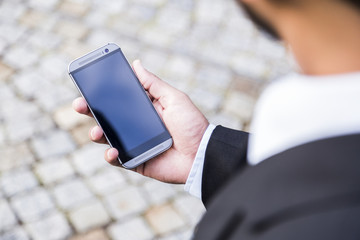 man in black suit holds mobile phone in his hand