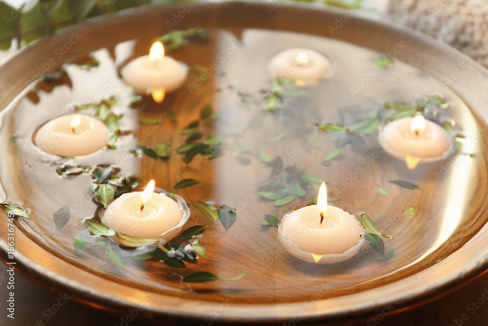 Beautiful spa composition with green leaves and candles on water