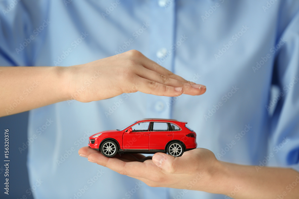 Travel insurance concept. Woman holding toy car