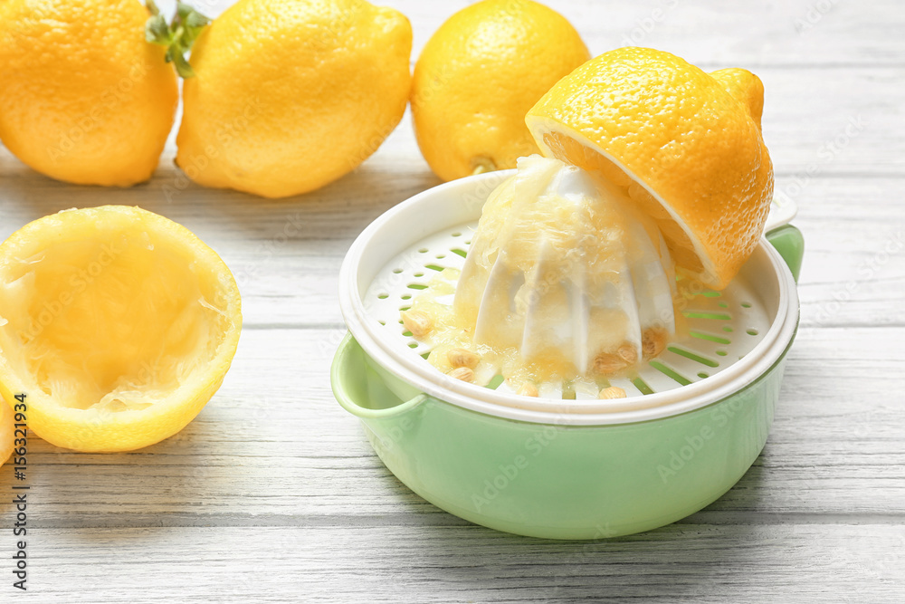 Squeezer and lemons on wooden table