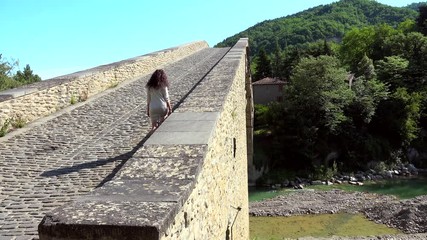 Poster - back of attractive woman In cream cocktail dress walking on the steep Renaissance bridge ramp