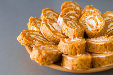 Cutting roll with carrot omelette and ricotta cheese with garlic on orange plate. 