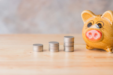 Piggy bank savings and coins on wooden tables with blurred backgrounds, saving for the future and investment planning