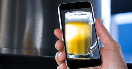 Poster - Hand taking picture of beer glass through smart phone at bar