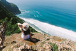 A girl sits on the edge of a cliff. A girl sits on the edge of a cliff and admire the sea. Amazing views.Travel on the island of Bali. Indonesia.