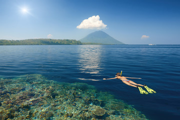 Canvas Print - woman swimming in mask in clear tropical waters on a background of excotic islands