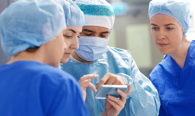 group of surgeons with smartphone at hospital