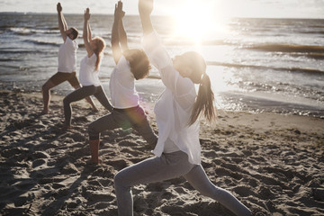 Canvas Print - group of people making yoga exercises on beach