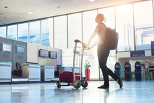 Woman With Luggage Trolley Walking To Airport Check-in Counter