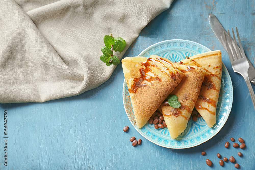 Tasty pancakes with chocolate syrup and nuts on plate
