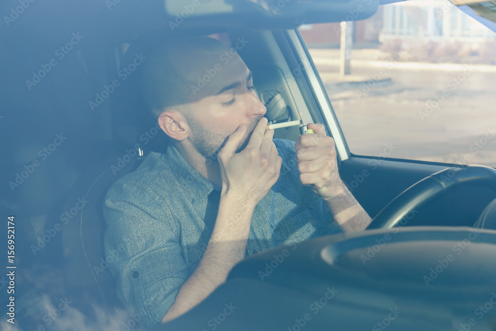 Handsome man smoking cigarette in car