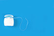 Dental floss in container on blue background