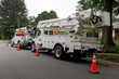 Rear and side view of parked communication utility trucks in residential neighborhood. Horizontal.