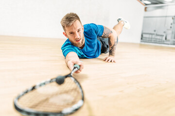 Squash training, player with racket lies on floor