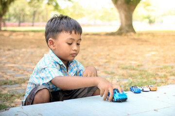 cute little boy play toy car in the green park