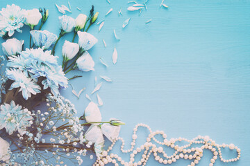 Top view of beautiful and delicate blue flowers arrangement next to pearls necklace