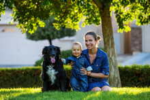 A Mother With Baby Son And Black Dog In Green Neighborhood