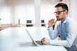 © bnenin - Concentrated young businessman is typing information on his laptop at the office.