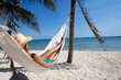 © plprod - femme couchée dans un hamac sur la plage  avec un chapeau de paille