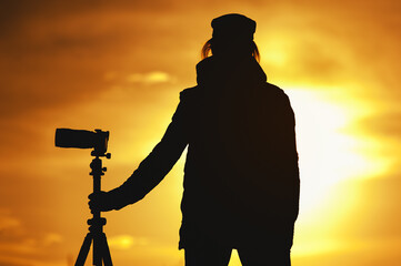 Wall Mural - Silhouette of Female photographer against sunset