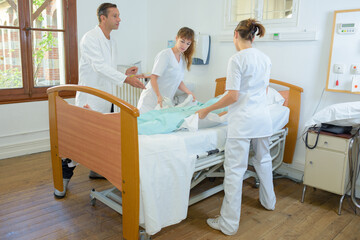 Nurses lifting patient under doctor's supervision