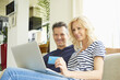 © sepy - Buying online. Shot of a happy mature couple buying online with their credit card at home.