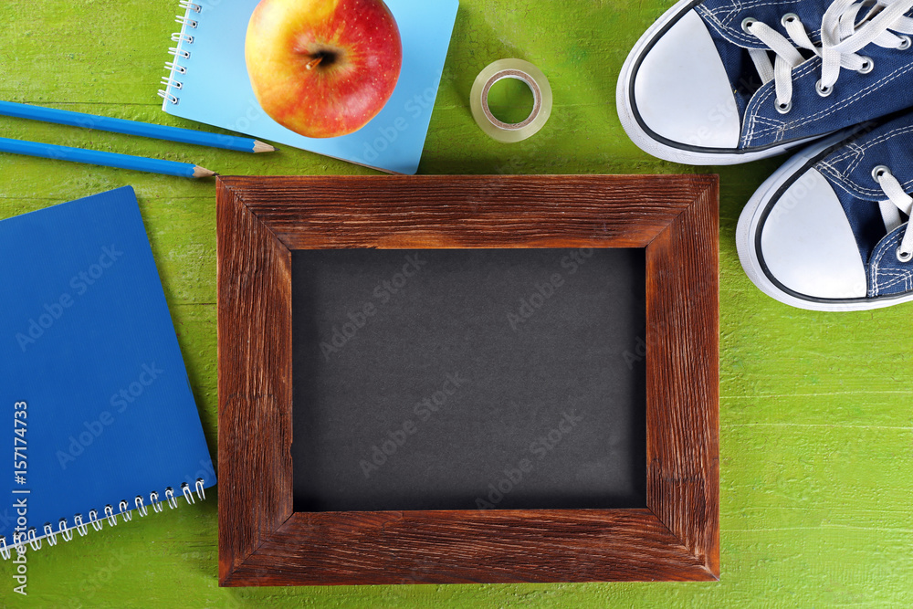 School stationery and small chalkboard on green background, top view