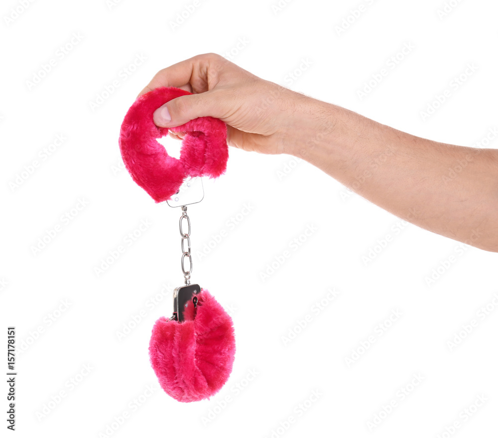 Man holding red furry handcuffs in hand on white background