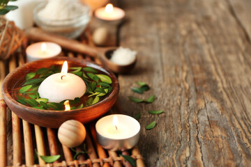 Wall Mural - Bowl with water, green leaves and burning candle on bamboo mat