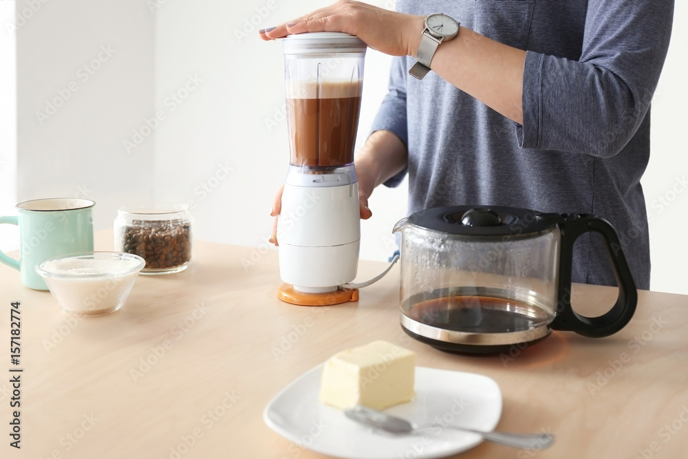 Woman using blender to make coffee with butter
