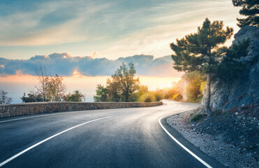 mountain road. landscape with rocks, sunny sky with clouds and beautiful asphalt road in the evening