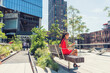 © Maridav - New York City lifestyle woman on mobile phone on urban high line park NYC. Tourist travel vacation girl sitting on beanch texting on smartphone app visiting Manhattan touristic attraction.