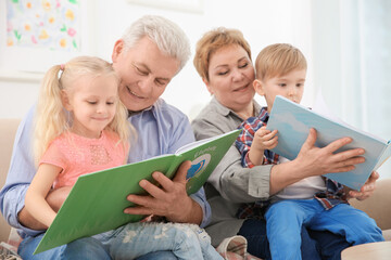 Wall Mural - Happy senior couple and their grandchildren reading books together at home