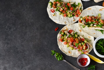 Mexican tacos with filling and guacamole sauce on a black background