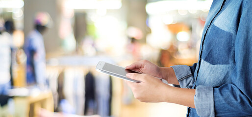 Hand using tablet over blur store with bokeh light background, banner, business and technology concept, digital marketing, seo, e-commerce