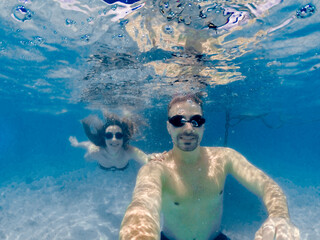 Wall Mural - Over under couple selfie. Having underwater fun on a beautiful island.