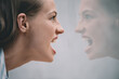aggressive stressed woman screaming at her reflection in mirror