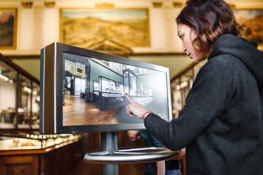 a woman in the museum uses the touchscreen monitor electronic guide, the concept of modern education