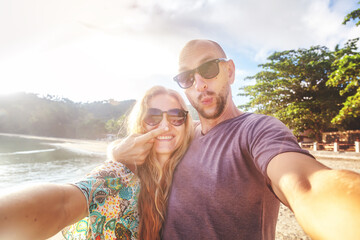 Wall Mural - beautiful young funny couple doing selfie on the shore of the tropical sea. vacation, travel, freedo