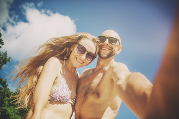Wall Mural - beautiful young funny couple doing selfie on the shore of the tropical sea. vacation, travel, freedo