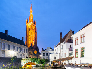 Church of Our Lady and bridge over water canal by night, Bruges, Belgium.