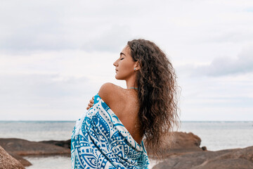 Wall Mural - beautiful young woman wrapped in a blanket on the beach