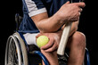 Cropped shot of disabled sportsman sitting in wheelchair and holding tennis racquet with ball