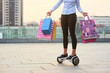 Woman holding colorful bags. Person riding gyroscooter. Ultimate shopping guide.