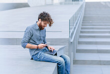 Young Man Looking Down At A Tablet And Smartphone